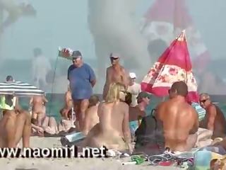 Naomi1 paja un joven compañero en un público playa